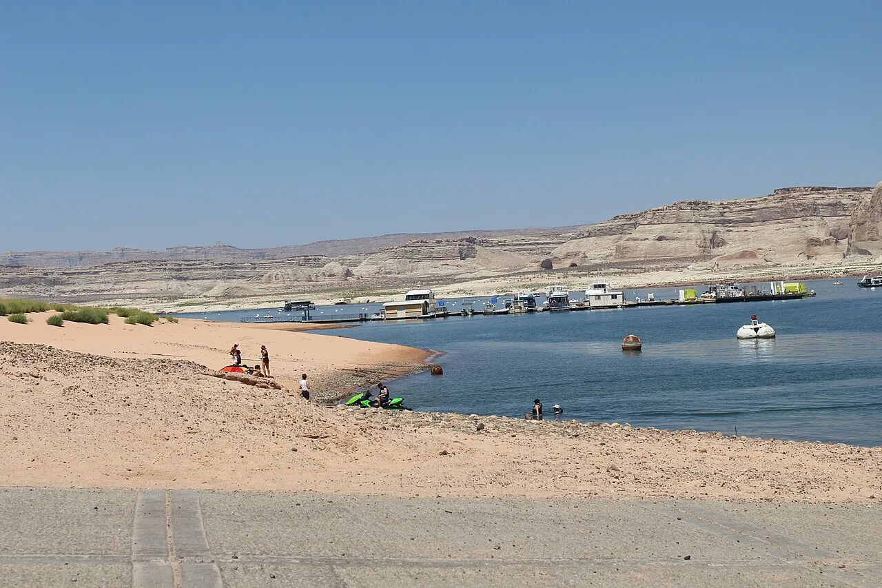 Groups of people recreating near waters edge of small beach area.
