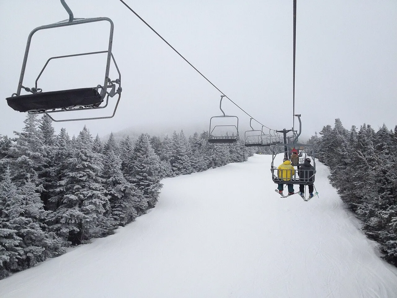 Skiers riding the ski lift up the slopes in Killington, Vermont during the winter.