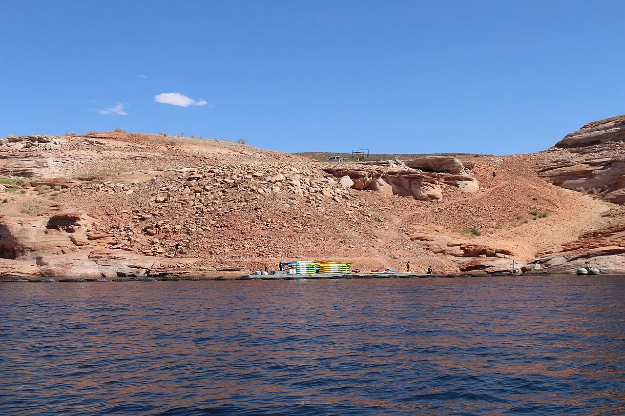 Paved road surrounding by rocky desert that ends near waters edge.