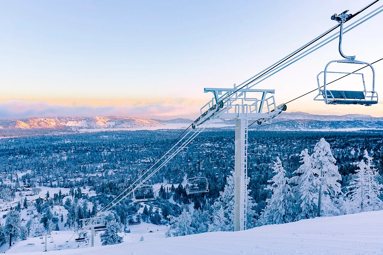 Ski lift over a snowy mountain with a forest in the background