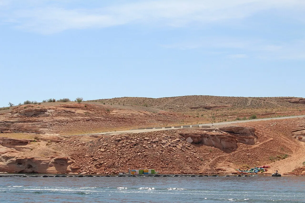 Paved road surrounding by rocky desert that ends near waters edge.